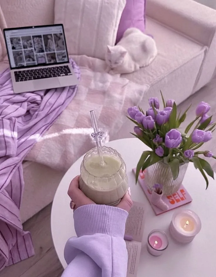 Cozy lavender living room with a laptop, a white cat, a drink and purple tulips